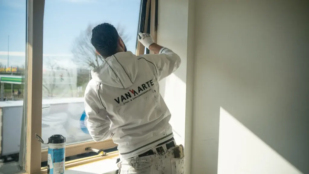 Schilder van Van Arte werkt aan een raamkozijn